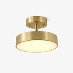 Clérachic brass ceiling light with a round canopy, a short stem and a flat disc head glowing warm white, on a plain light backdrop.