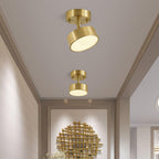 Two Clérachic brass ceiling lights in a pale corridor, one with its disc head tilted to the side, a gold wall panel ahead.