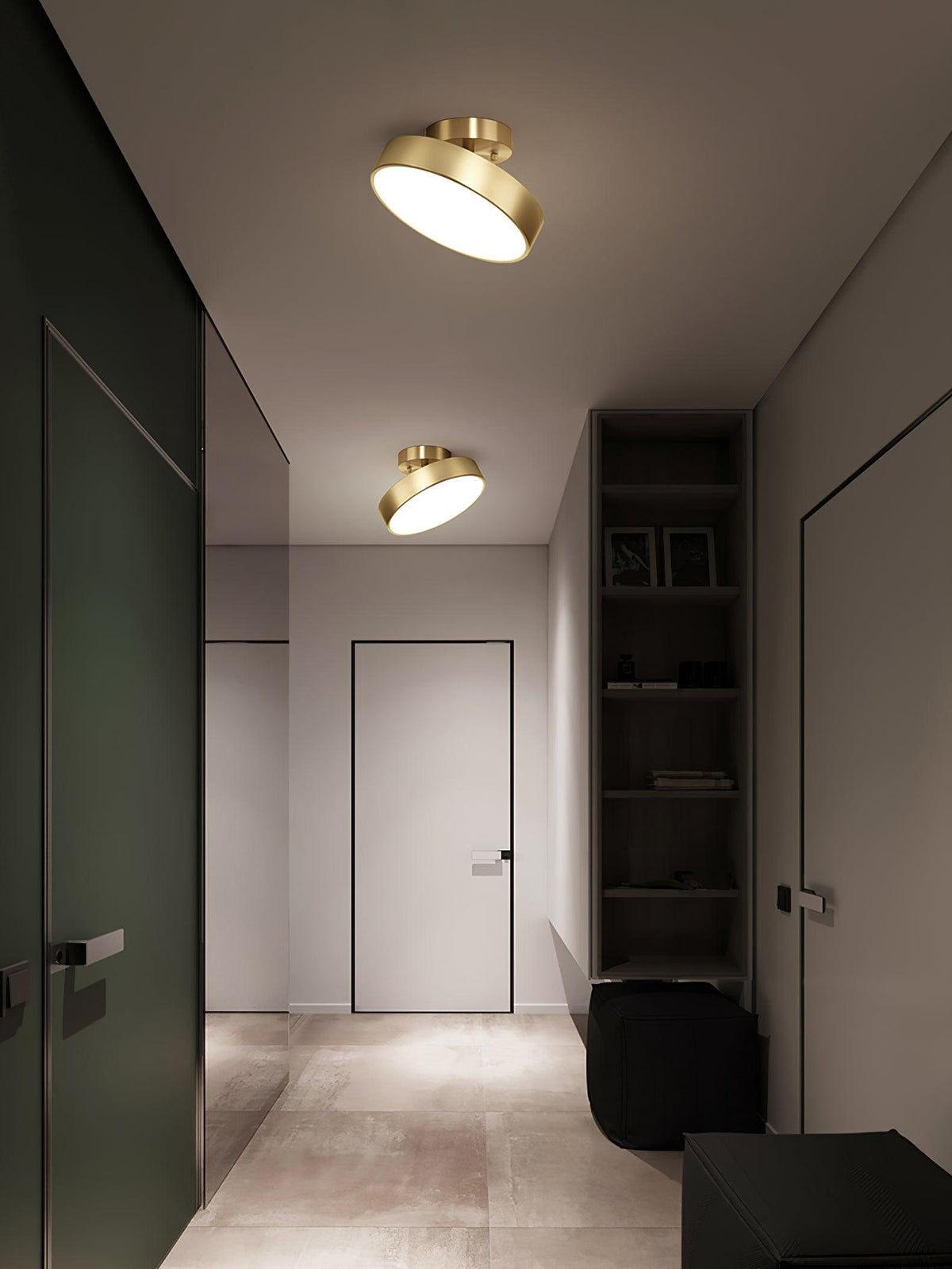 Two brass Clérachic ceiling lights, one tilted, in a hallway with a dark green door and a tall black bookshelf.