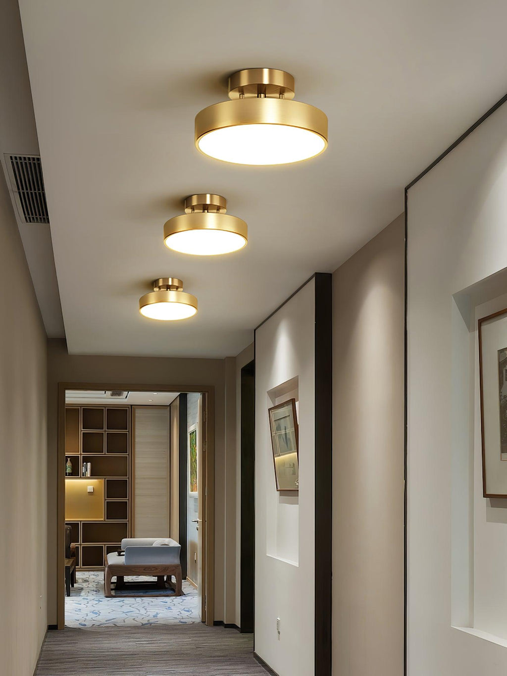 Three Clérachic brass ceiling lights of descending size along a corridor, with a bench and open shelves in the room beyond.