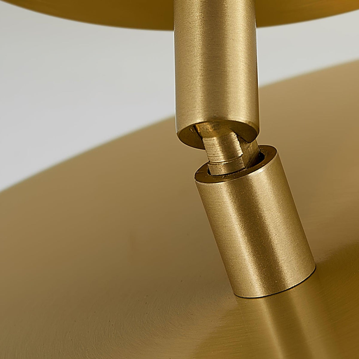 Close view of the swivel joint on this Clérachic brass ceiling light, where the stem turns to tilt the disc head.