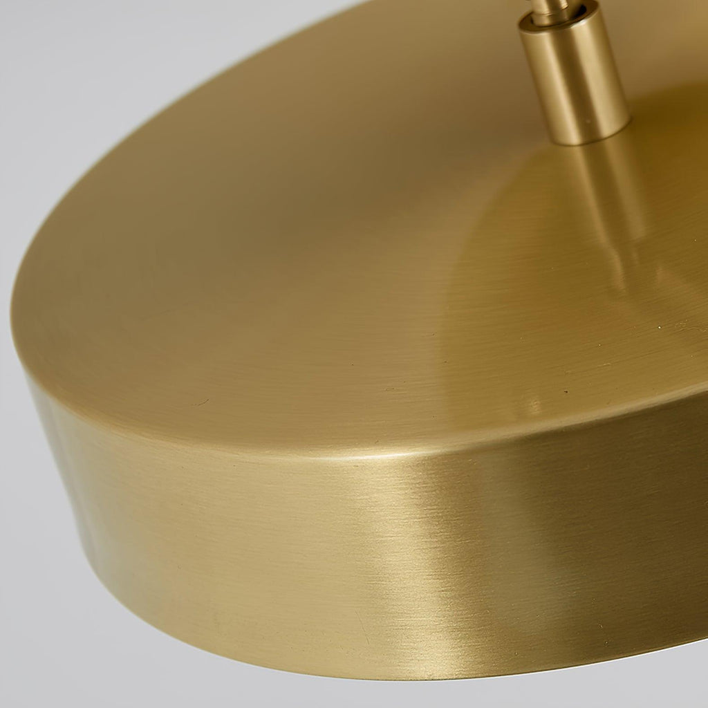 Close view of the tilted brass disc on this Clérachic ceiling light, with the swivel stem entering at the top.