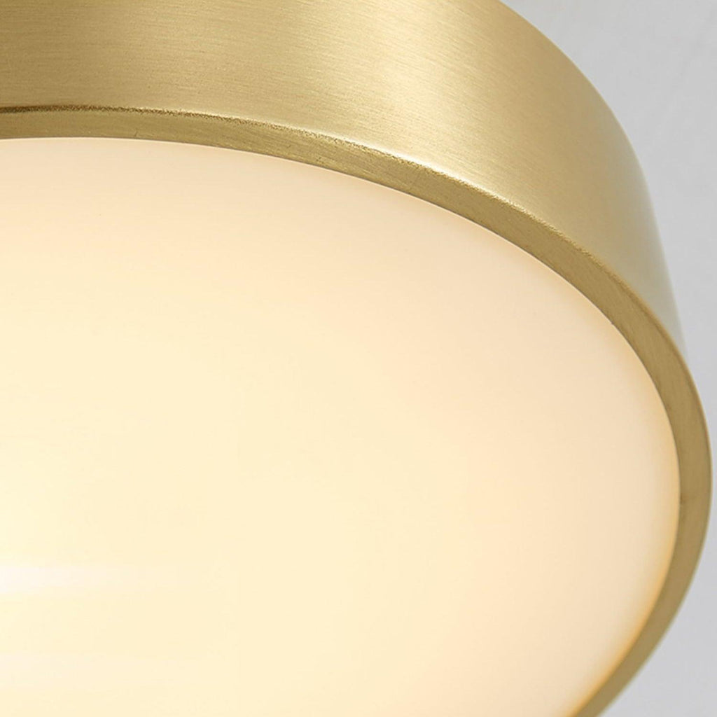 Close view of the lit diffuser and brass edge on this Clérachic ceiling light, the glow soft and even across the disc.
