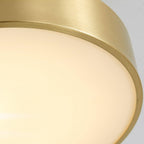 Close view of the lit diffuser and brass edge on this Clérachic ceiling light, the glow soft and even across the disc.