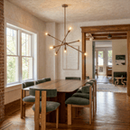 Clérachic vintage brass sputnik chandelier lit above a long dining table in a house with an exposed brick wall.