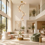 Clérachic vine chandelier lit in a double-height living room, above a curved cream sofa, a green armchair and a brass side table.