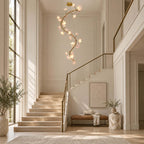 Clérachic chandelier lit in a tall stairwell with a brass handrail, above a stone landing with a leather bench and a small side table.