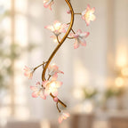 Close view of the brass vine and pink-white ceramic blooms on this Clérachic chandelier, lit warm against a soft blurred room.