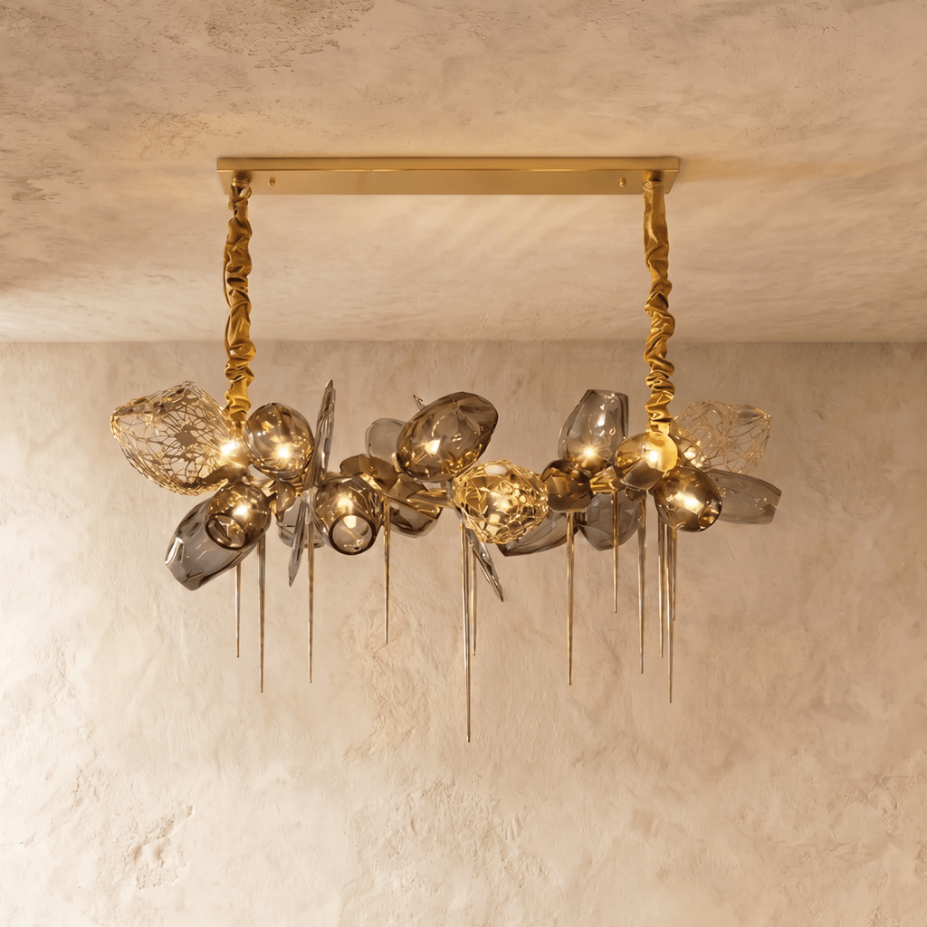 Clérachic rectangular-canopy chandelier with grey glass globes, openwork brass shades and pointed brass spikes, lit warm.