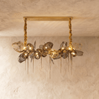 Clérachic rectangular-canopy chandelier with grey glass globes, openwork brass shades and pointed brass spikes, lit warm.
