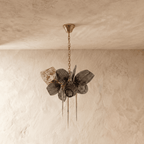 Clérachic chandelier with ribbed smoked glass petals, switched off, hanging from a fine brass chain against a limewash wall.