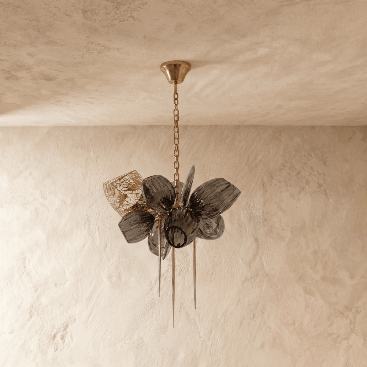Clérachic chandelier with ribbed smoked glass petals, switched off, hanging from a fine brass chain against a limewash wall.