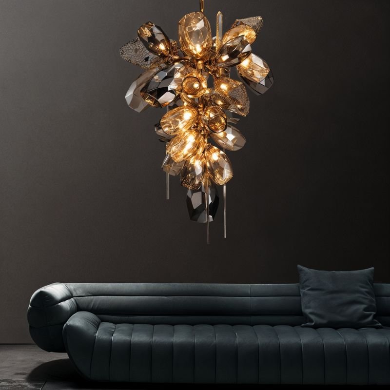 Clérachic cluster chandelier of amber and smoked glass facets glowing above a low dark leather sofa against a charcoal wall.