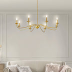 A Clérachic brass chandelier hangs in front of a panelled grey wall, above a cream sofa with fluffy cushions.