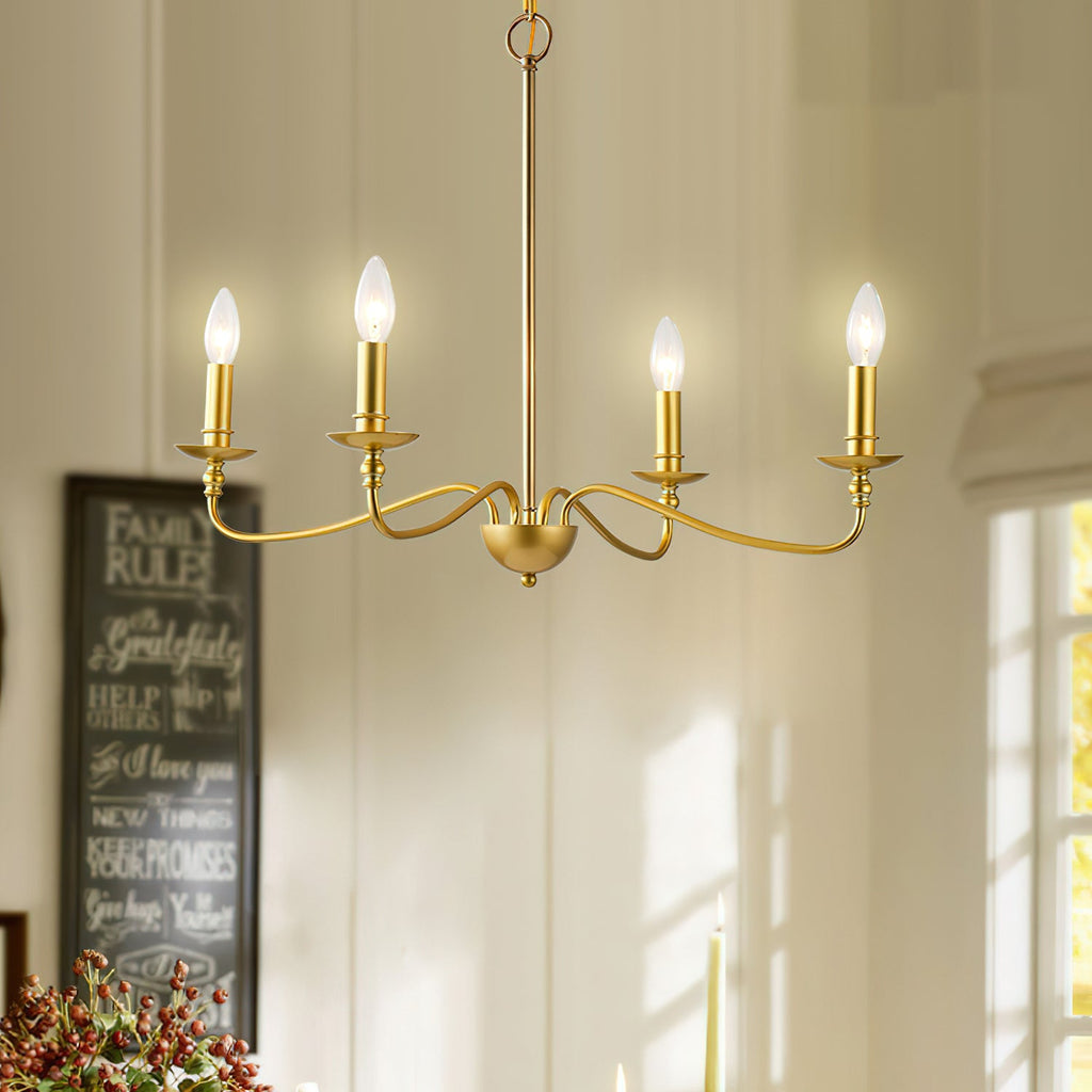 A four-arm Clérachic brass chandelier glows in a sunlit dining room beside a window and a chalkboard sign.
