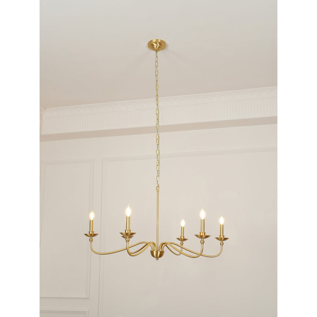 A Clérachic brass chandelier lit under a high ceiling, with moulded wall panels and a thin chain above.