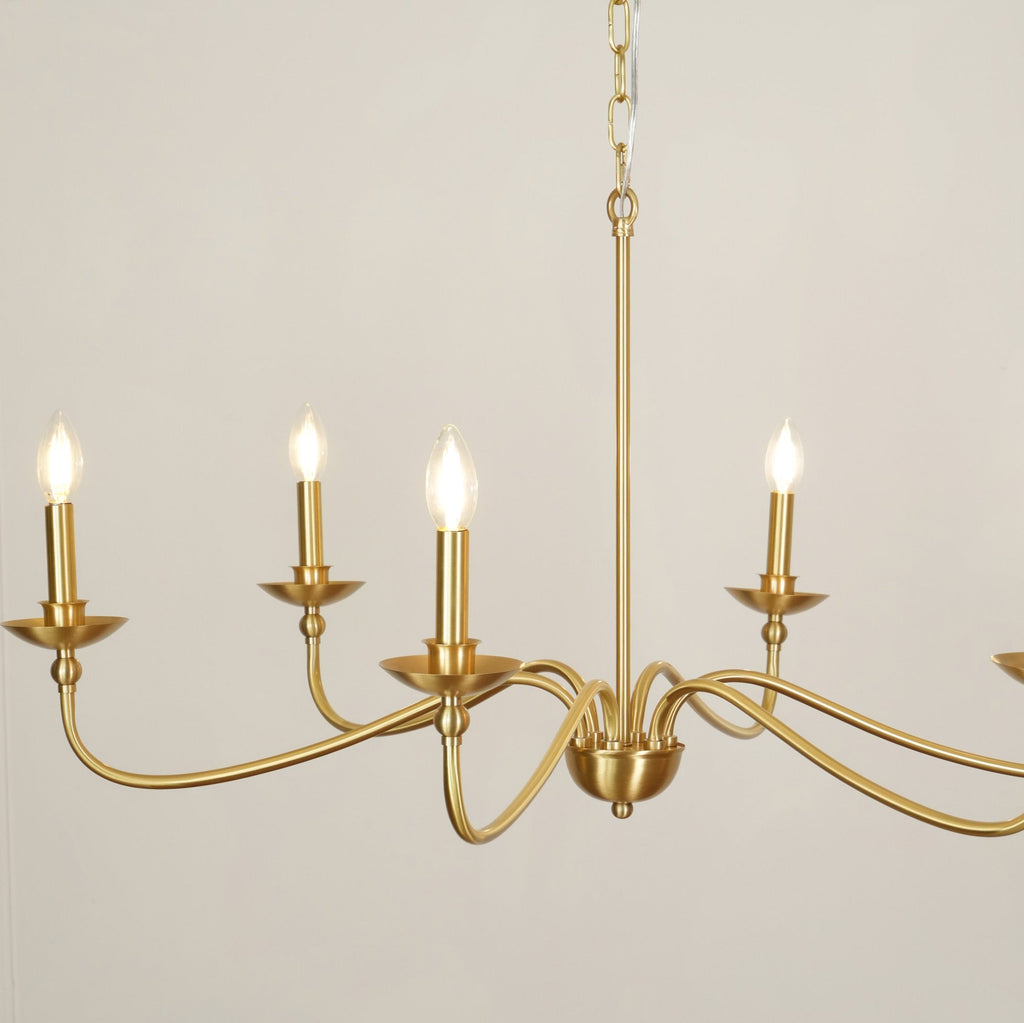 Close view of the lit candle-style bulbs and curved brass arms on this Clérachic chandelier, with the rod above.