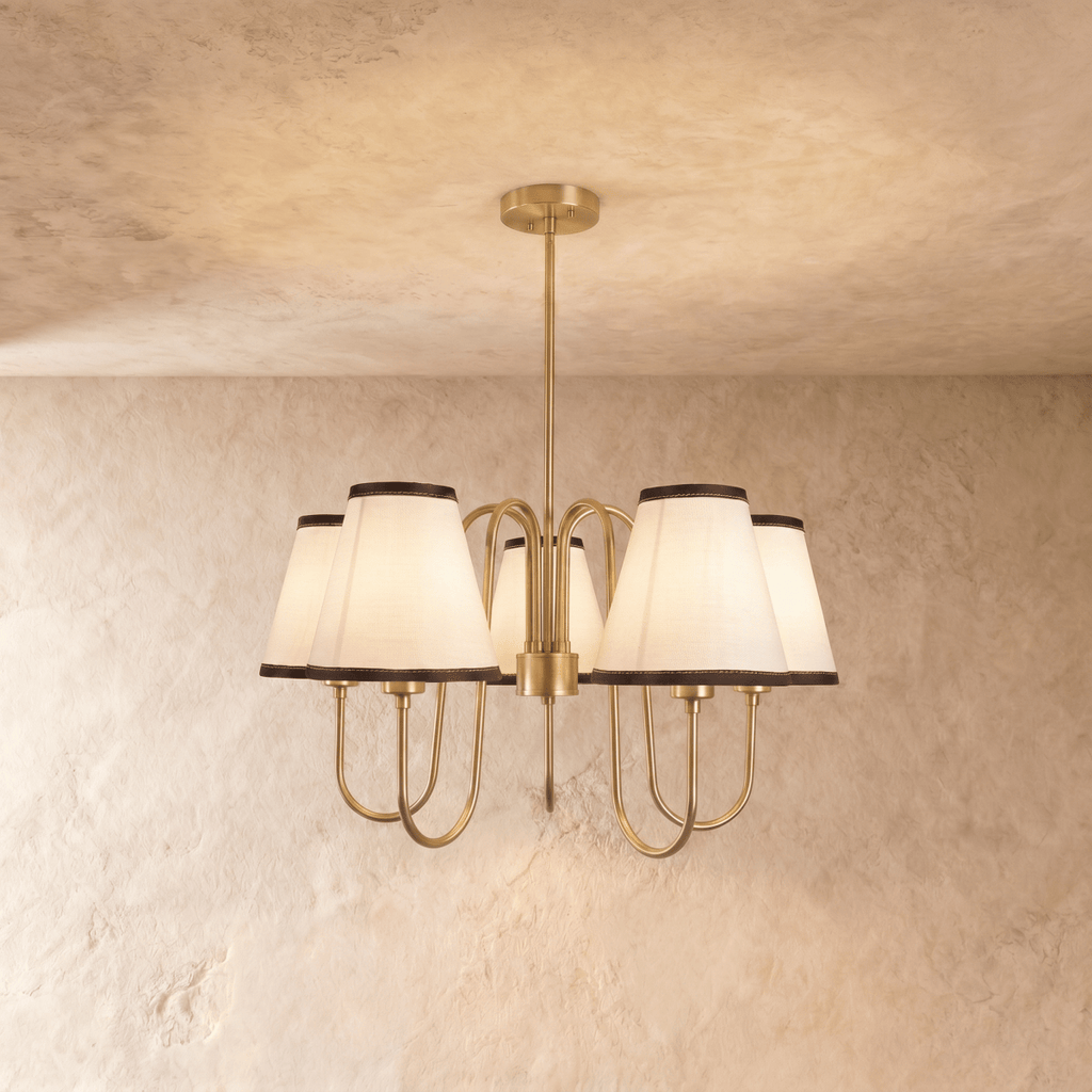 Clérachic chandelier in polished brass, five ivory shades with dark trim arranged in a circular spread.