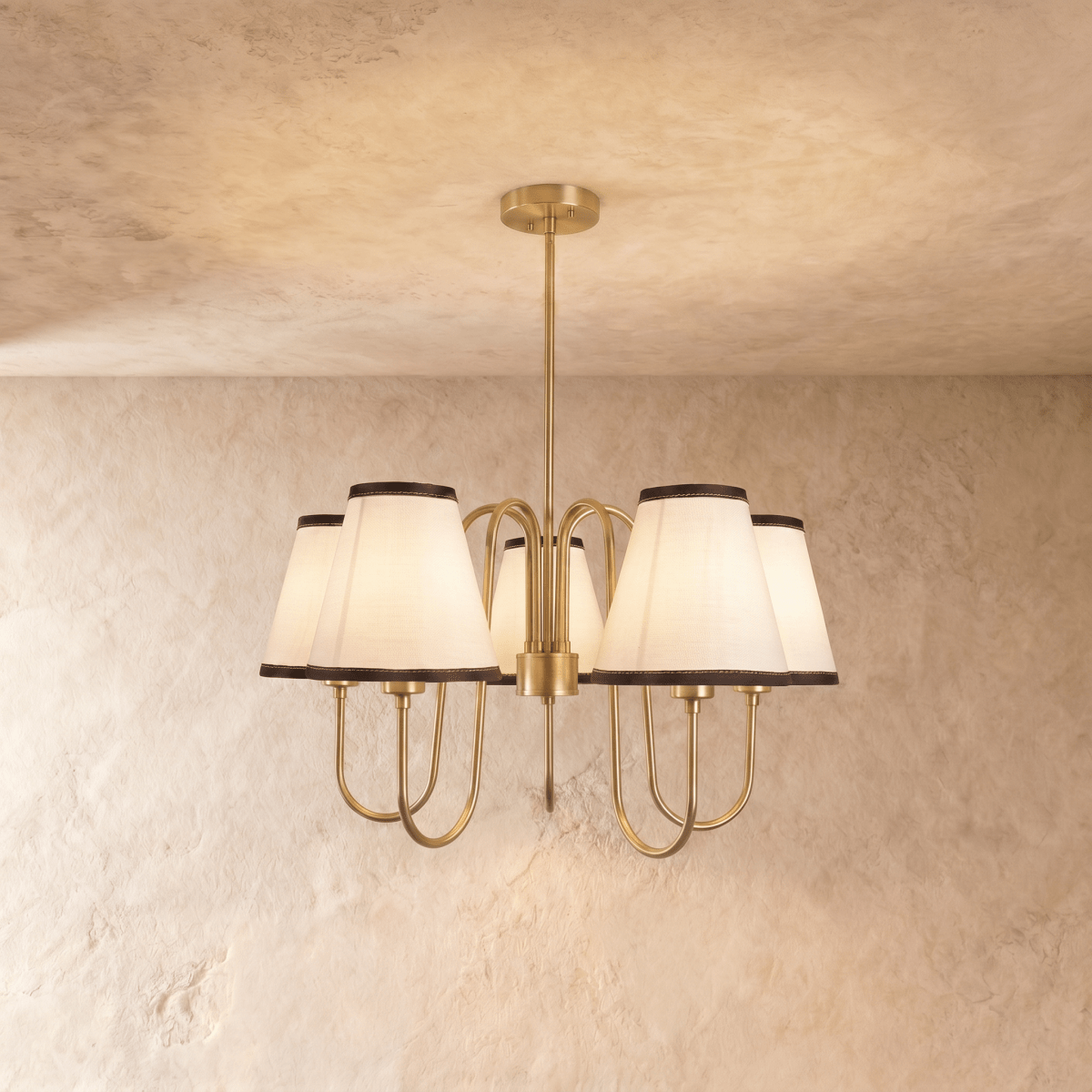Clérachic chandelier in polished brass, five ivory shades with dark trim arranged in a circular spread.