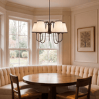 This black Clérachic chandelier hangs above a round table inside a curved upholstered banquette.