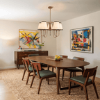 This brass Clérachic chandelier hangs above a dining table flanked by bold abstract paintings.
