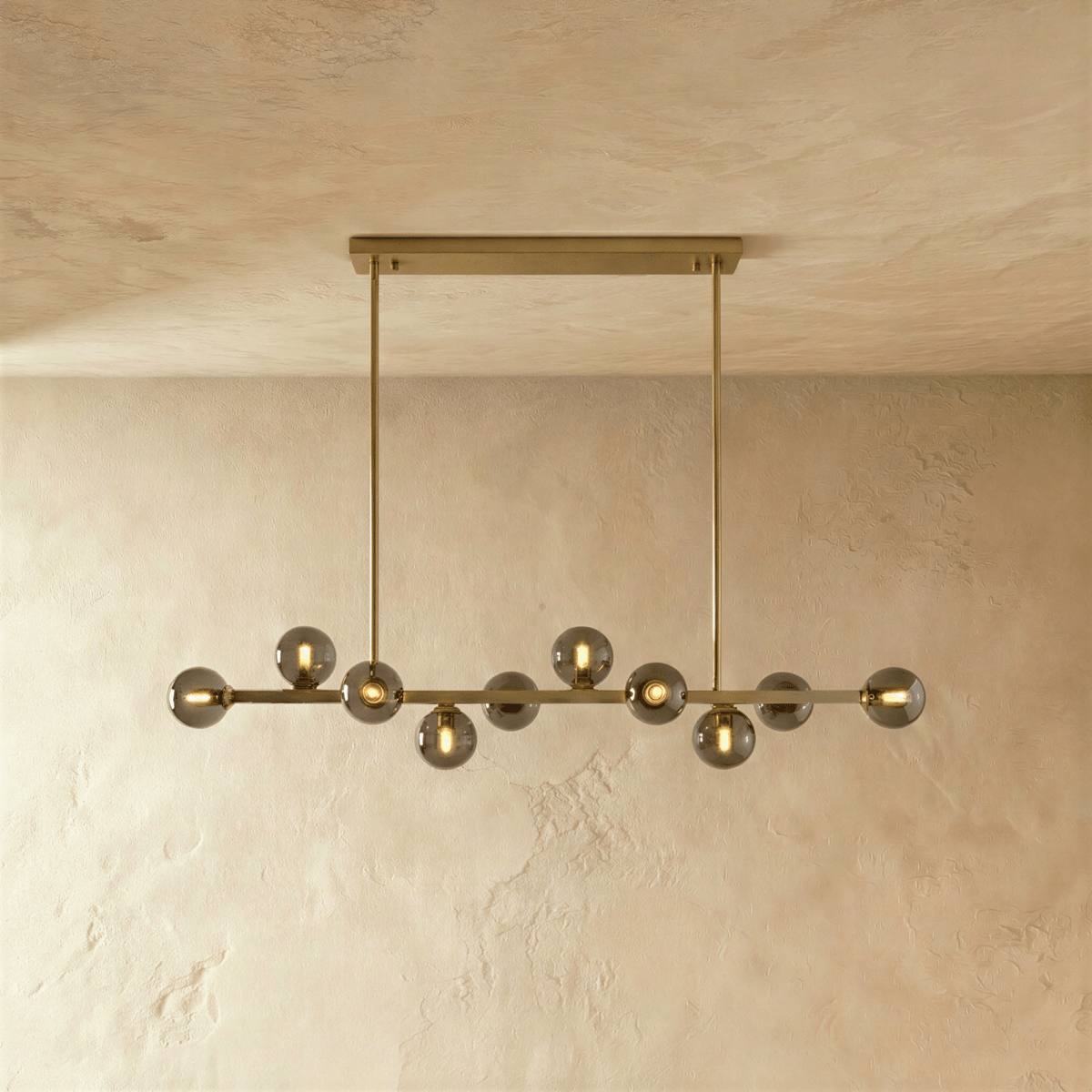 Clérachic brass chandelier with clear glass globes and warm filament bulbs, mounted on a horizontal bar plate.