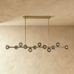 Clérachic linear chandelier shows a dense row of clear glass globes suspended from a horizontal bar plate.