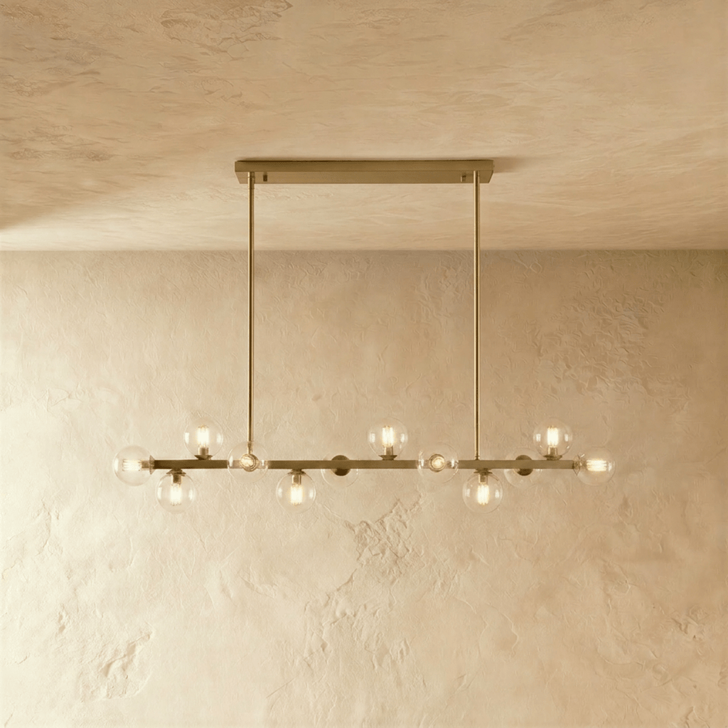 Clérachic brass chandelier with clear glass globes glowing warm, suspended from a horizontal bar plate.