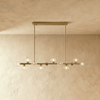 Clérachic brass chandelier with clear glass globes glowing warm, suspended from a horizontal bar plate.