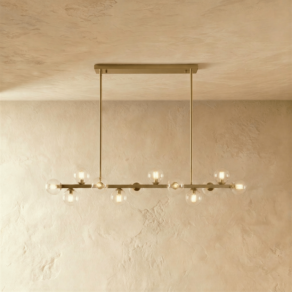 Clérachic brass chandelier with clear glass globes glowing warm, suspended from a horizontal bar plate.