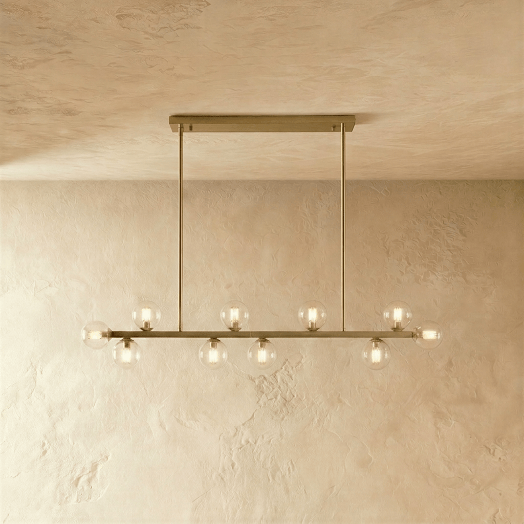 Clérachic linear chandelier shows clear glass globes and brass stems along a horizontal ceiling bar plate.