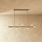 Clérachic brass chandelier with a shorter row of clear glass globes, mounted on a horizontal bar plate.