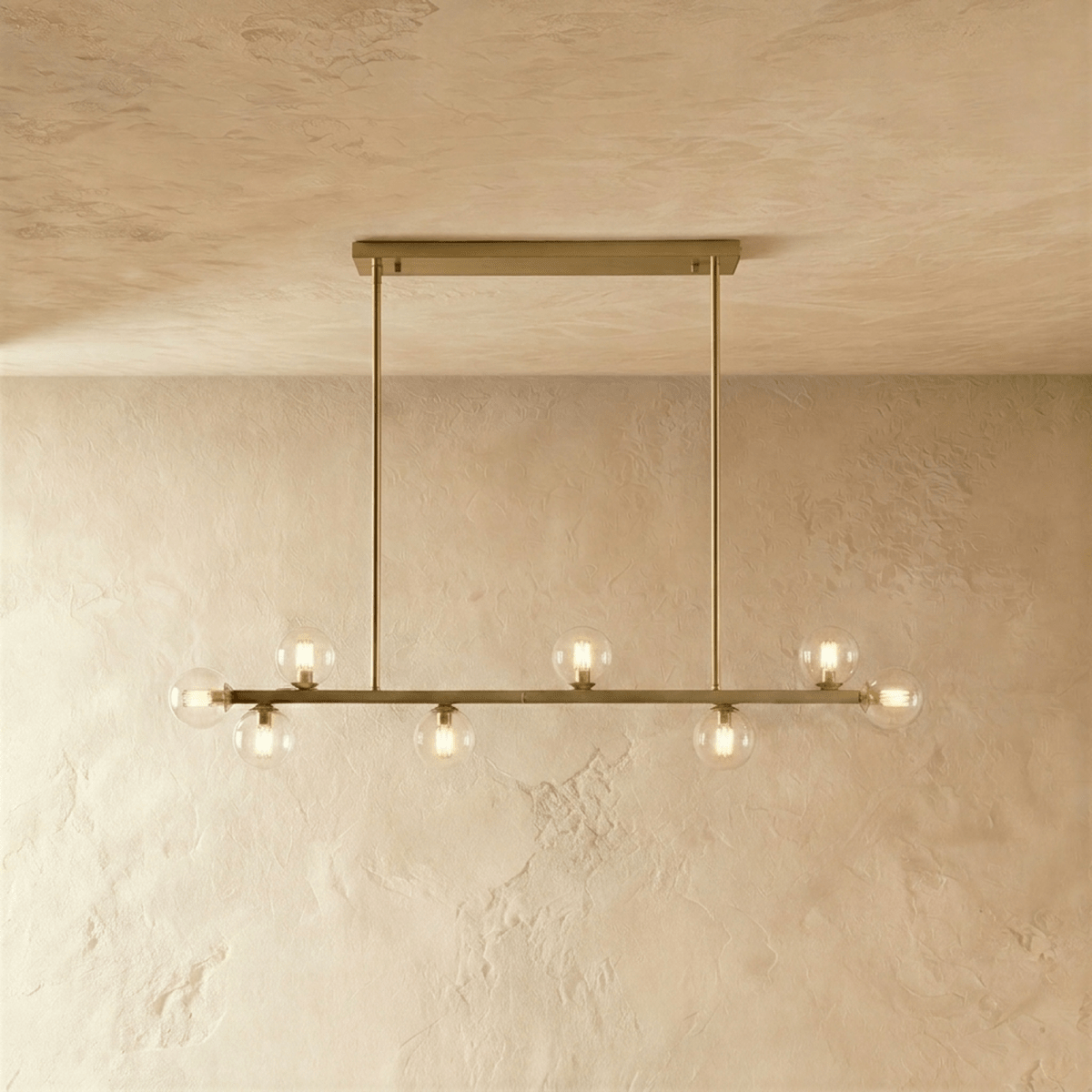 Clérachic brass chandelier with a shorter row of clear glass globes, mounted on a horizontal bar plate.