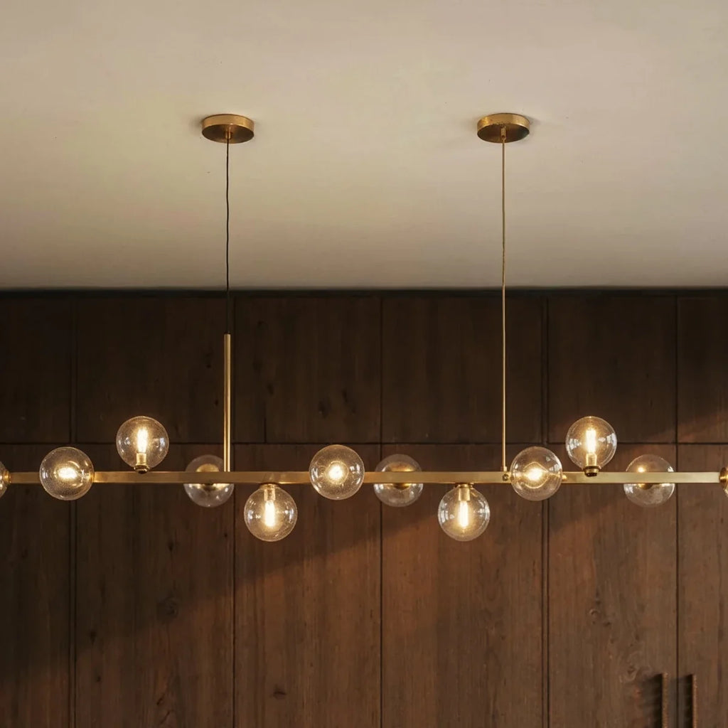 Clérachic chandelier detail shows twin round ceiling canopies and clear glass globes against wood paneling.