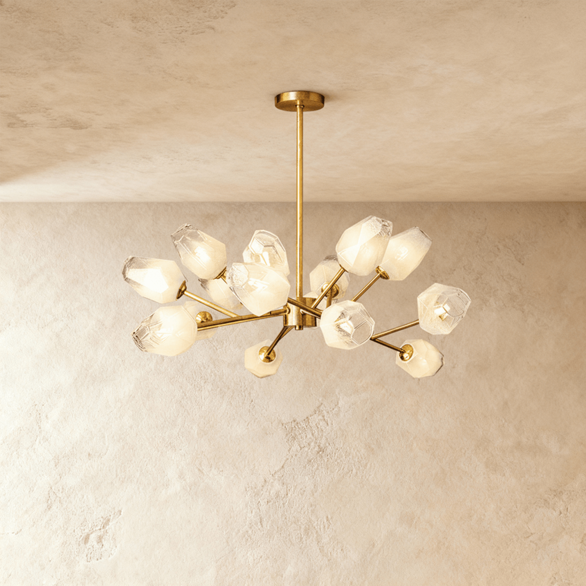 Clérachic brass chandelier with a ring of frosted faceted glass heads on thin arms, shown from slightly below on limewash.