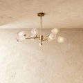 Clérachic nine-head brass chandelier with frosted faceted glass shades on slim arms below a round brass canopy.
