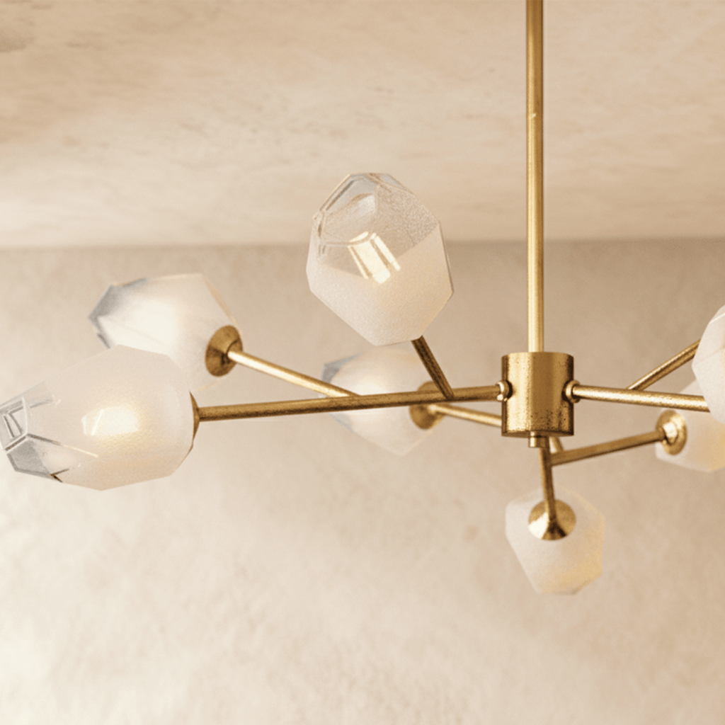 Clérachic chandelier detail: brass centre hub, slim arms and frosted faceted glass heads, one clear-topped shade lit.