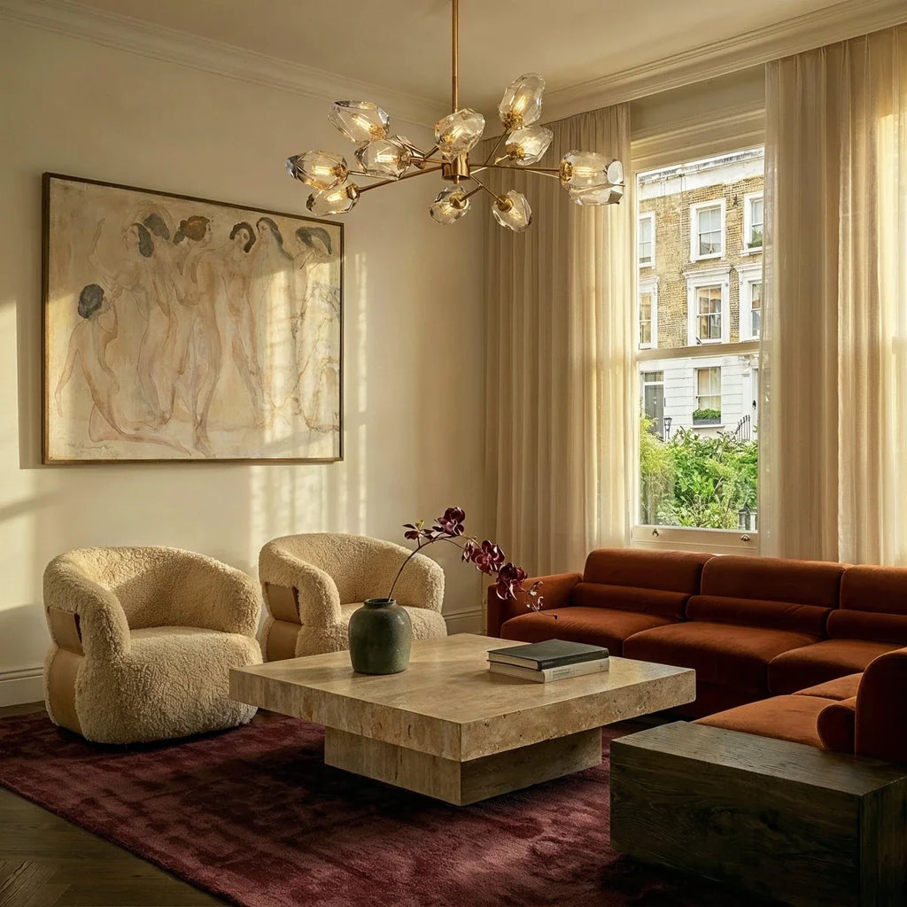 Clérachic brass chandelier with faceted glass heads lit above a travertine coffee table in a sunny living room.
