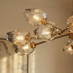 Close view of Clérachic chandelier glass heads, rippled clear glass with exposed filament bulbs on brass arms.