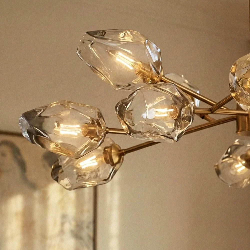 Close view of Clérachic chandelier glass heads, rippled clear glass with exposed filament bulbs on brass arms.