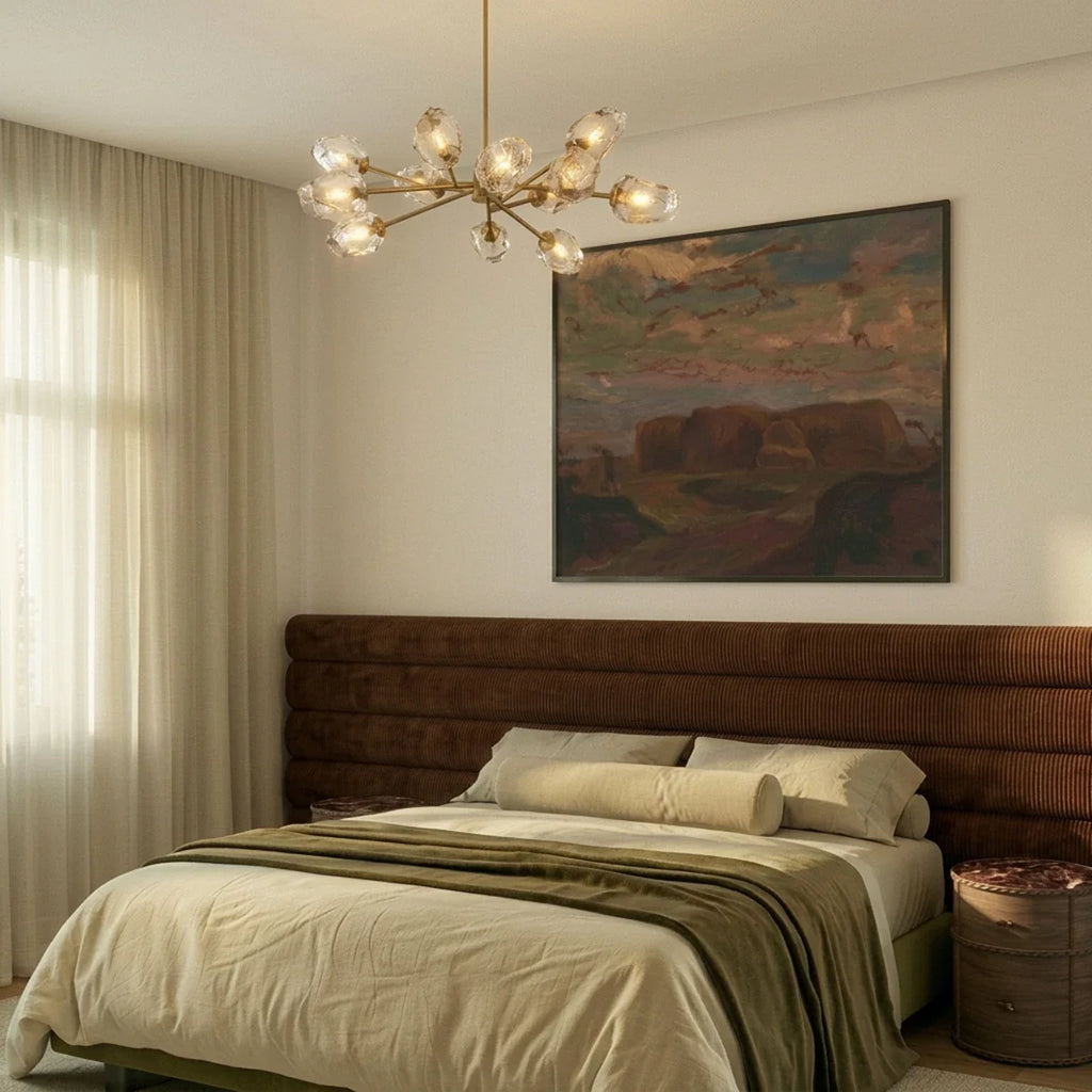Clérachic brass chandelier lit above a bed with a rust corduroy headboard and a large landscape painting.