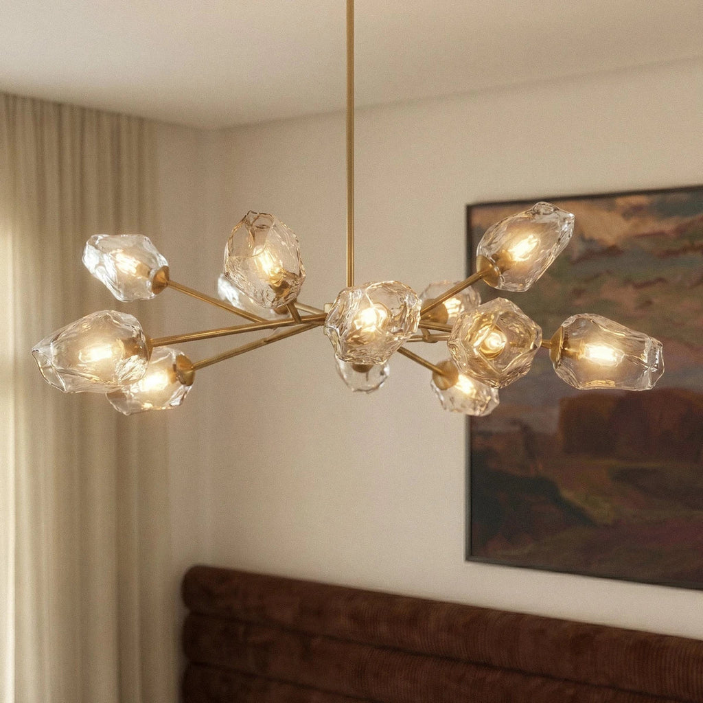 Clérachic brass chandelier with clear rippled glass shades and warm bulbs, hung in a bedroom beside a framed painting.