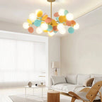 Clérachic chandelier with frosted globes and teal, yellow and coral discs on brass arms above a bright living room.