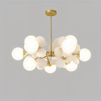 Clérachic brass chandelier with a dense cluster of glowing frosted glass globes and cream discs.