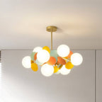 Clérachic chandelier with frosted globes and orange, yellow and mint discs on a brass rod, near a white wall.
