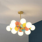 Clérachic brass chandelier with frosted globes and pastel orange, mint and yellow discs against a blue wall.