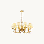 This Clérachic brass chandelier on a plain white backdrop, with curved arms, a slim baluster stem and pleated white fabric shades.