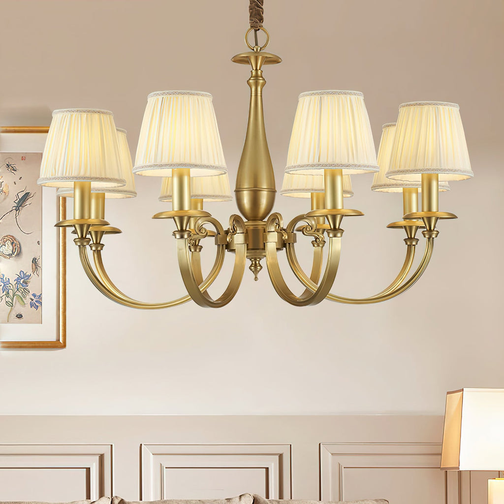 Close crop of this Clérachic brass chandelier, with curved brass arms and pleated shades, against a cream panelled wall.