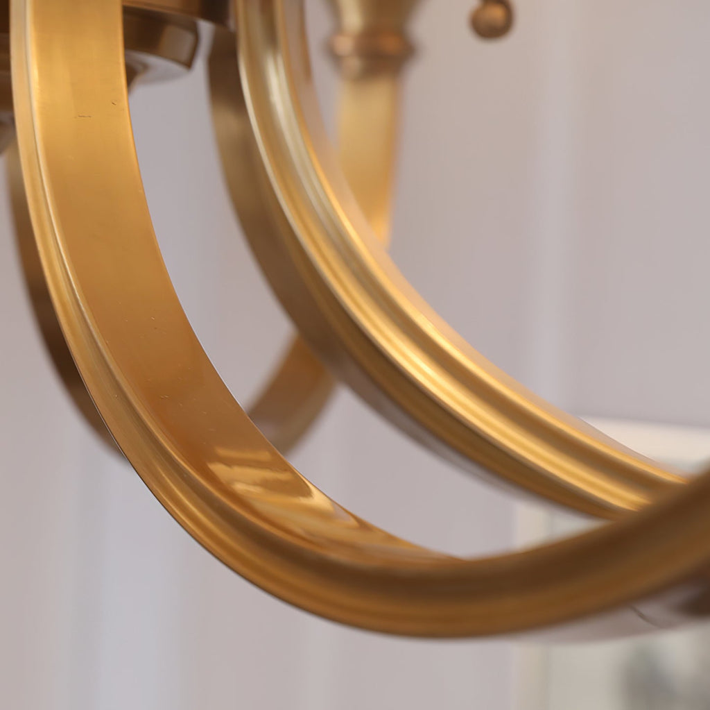 Close view of the broad curved brass arms of this Clérachic chandelier, showing the flat, brushed brass finish.