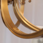 Close view of the broad curved brass arms of this Clérachic chandelier, showing the flat, brushed brass finish.